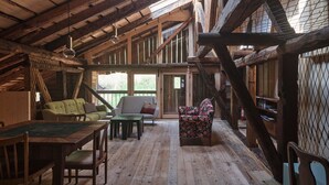 Un interior rústico con vigas de madera, techo elevado, una mesa de comedor y un sofá.
