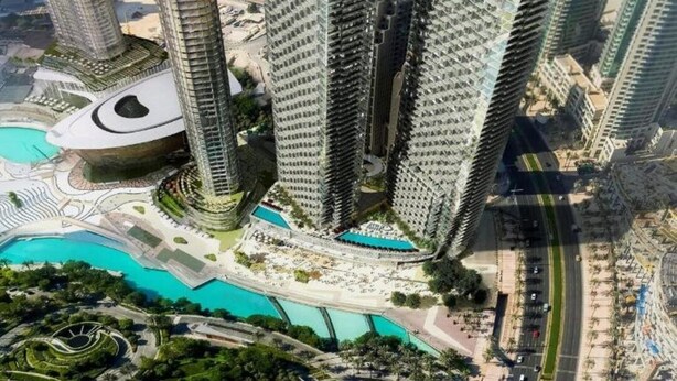 Um complexo de edifícios altos com vários arranha-céus, uma praça central com design circular e uma área ajardinada ao redor, com caminhos e piscina.