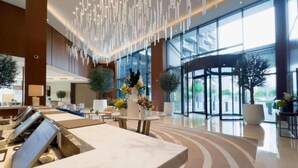 Um lobby moderno com uma receção de mármore, janelas amplas e uma porta giratória.