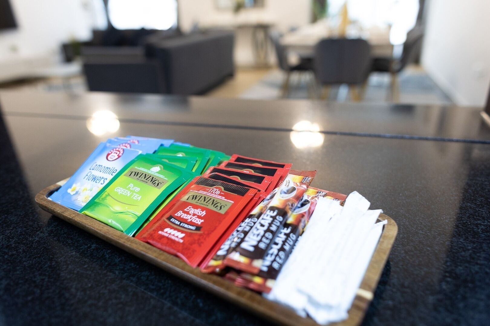 A tray with various tea and coffee products on a table in a modern kitchen setting.
