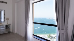 Una habitación con un ventanal grande que ofrece vistas al mar, un aparador con espejo y una lámpara.