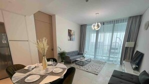 Un saló modern amb zona de menjador, sofà i una finestra gran amb cortines.