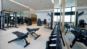 Un gimnàs modern amb diversos equips per a exercici, incloent bancs, pèses i aparells de musculació.