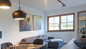 Ein modernes Wohnzimmer mit einer Couch, einem Esstisch und Pendelleuchten.