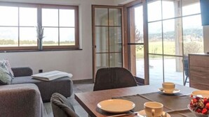 Ein moderner Essbereich mit einem Tisch für zwei Personen, einer Couch und einem großen Fenster mit Blick auf die Landschaft.