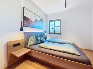 A modern bedroom with a built-in bed, a window with a view, and a painting on the wall.