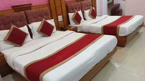 Ein Hotelzimmer mit zwei Betten, jeweils mit weißer Bettwäsche und roten Akzenten, sowie einem hölzernen Kopfteil.