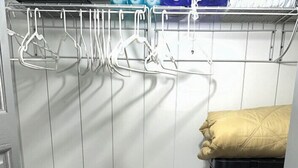 Un placard de rangement avec des étagères, un banc et des barres pour suspendre les vêtements.
