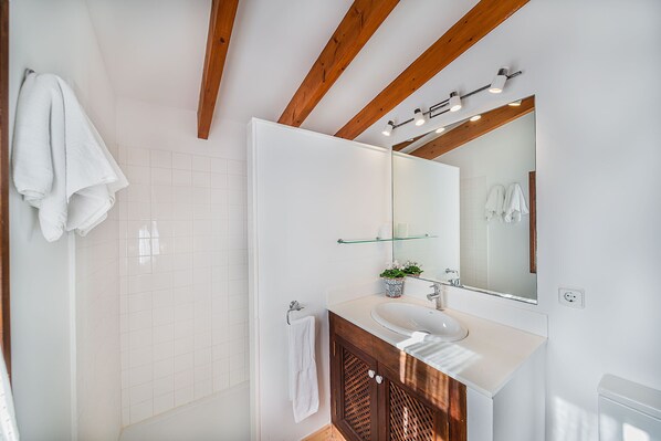 Une salle de bain moderne avec un lavabo blanc, un meuble-lavabo en bois et un grand miroir.