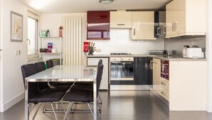A modern kitchen with a dining table, chairs, a stove, oven, microwave, and cabinets. - GuestReady - Spacious 2Bed in Edinburgh (Edinburgh)