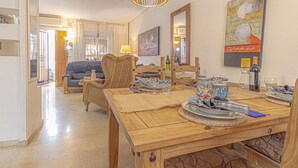 Comedor con una mesa de madera dispuesta para cuatro personas, rodeado de sillas de mimbre.