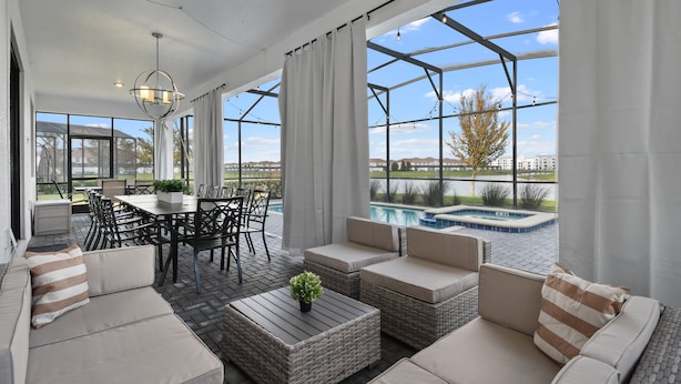 Amplio patio amoblado con mobiliario exterior, una mesa de comedor y vistas a una piscina.