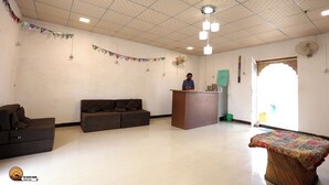 A reception area with a wooden desk, two sofas, a patterned table, and a decorative banner. - The Desert Dhani Resort (Jaisalmer)