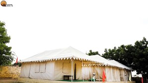 A large white tent with a flat roof, a bench, and a small table in front. - The Desert Dhani Resort (Jaisalmer)