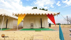 A desert tent with a green carpet and a chair in front. - The Desert Dhani Resort (Jaisalmer)