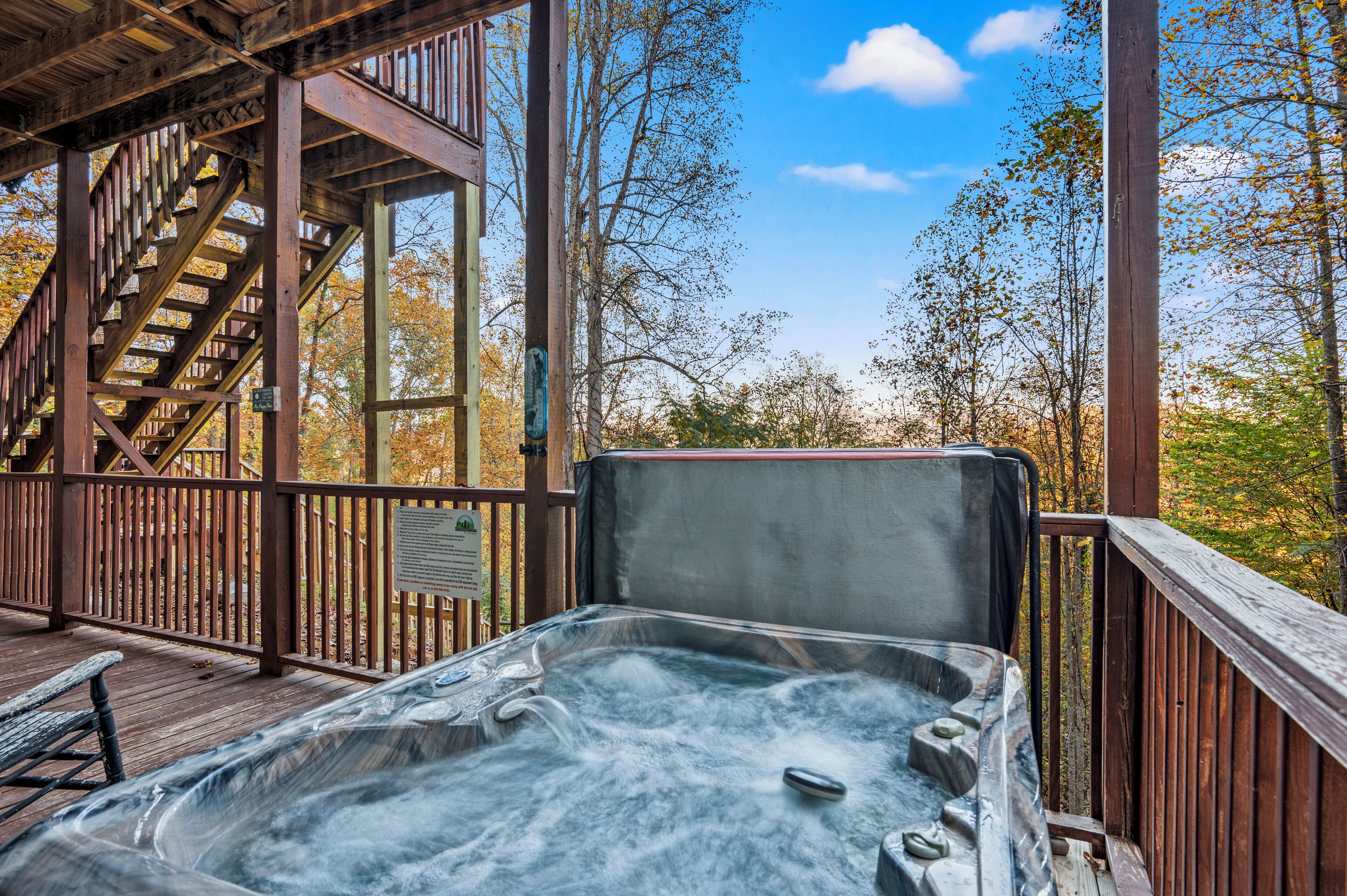 A hot tub on a wooden deck with a staircase leading to a covered area.