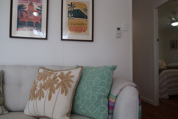 A living room with a sofa, two framed pictures, and a door leading to another room.