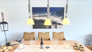 A dining table set with wine glasses, a bottle, and candles, with a forest landscape painting above. - Schwarzwaldblick VI by Interhome (Bernau)