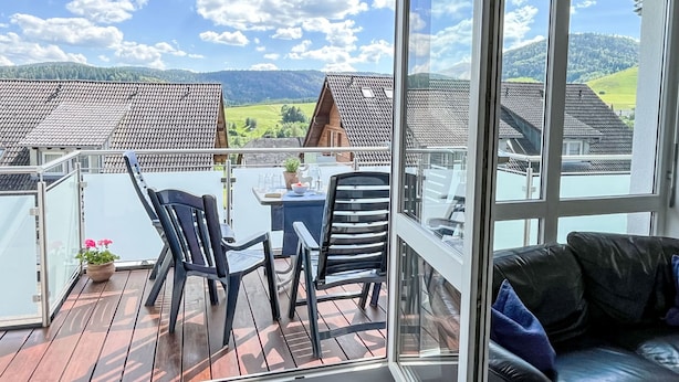 A balcony with a view of a village, a table with chairs, and a sofa. - Schwarzwaldblick VI by Interhome (Bernau)