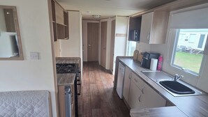 A compact RV kitchen with a stove, sink, and a small refrigerator. - Steve caravan Sleeps 6 with Free Parking (Rhyl)