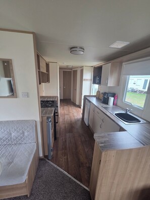 A compact RV kitchen with a stove, sink, and a small refrigerator.