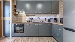 Une cuisine moderne avec des meubles gris, un plan de travail en bois et des appareils électroménagers en acier inoxydable.