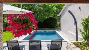 Un espace piscine agrémenté de deux chaises longues et d’une composition florale suspendue.