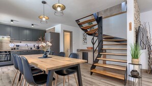 Une cuisine moderne avec des meubles de couleur sombre, une table à manger en bois et un escalier en colimaçon.