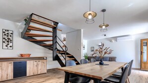 Une cuisine moderne avec des meubles en bois, une cuisinière encastrée et un escalier doté d’une rampe noire.