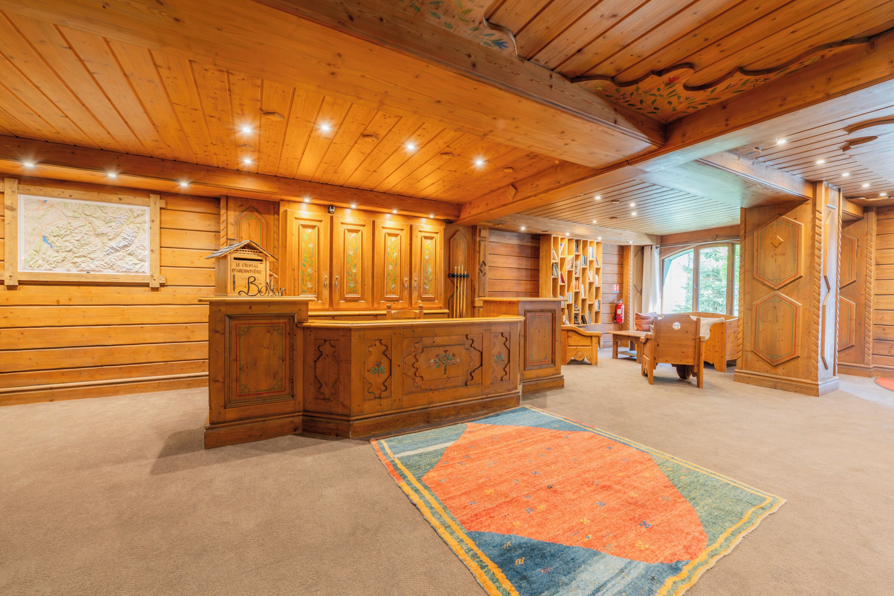 Un intérieur en bois avec un comptoir central en bois, des étagères et un grand tapis.
