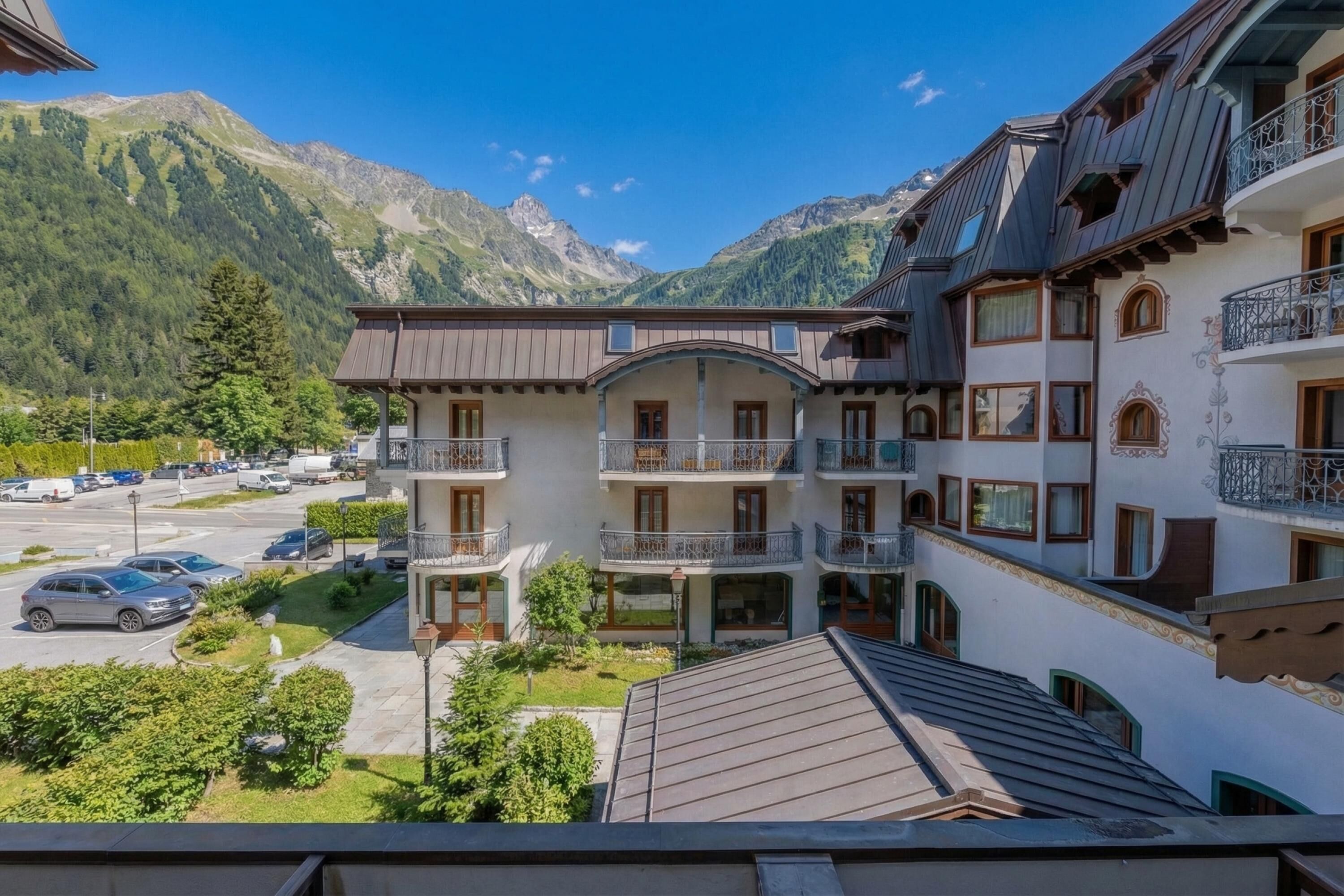 Un hôtel à plusieurs étages doté de balcons, d’un parking et offrant une vue sur la montagne.