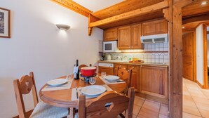 A wooden dining table with chairs, a red pot, wine glasses, and a white plate. - Le Cristal GM9 Mountain View, Pool, Parking & Free WiFi, Argentière (Chamonix), France (Argentière (Chamonix))