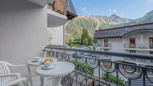 A balcony with a table and chairs, a mountain view, and a parking area. - Le Cristal GM9 Mountain View, Pool, Parking & Free WiFi, Argentière (Chamonix), France (Argentière (Chamonix))