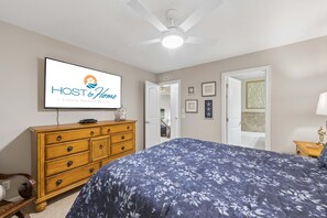 Ein Schlafzimmer mit Bett, Kommode, Fernseher der 'HOST & Home - Luxury Vacation Rentals' zeigt und einem Deckenventilator.