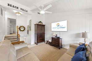 Ein Wohnzimmer mit Sofa, Fernseher und Deckenventilator, mit einem Schild, auf dem 'HOST & Home - Luxury Vacation Rentals' steht.