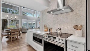 Uma cozinha moderna com uma ilha grande, fornos embutidos e um exaustor de aço inoxidável.