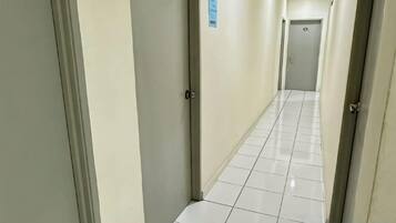 Käytävä, jossa on laatoitettu lattia ja ovet molemmin puolin.