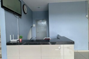 A reception area with a black counter, a clock, a door, and a potted plant. - Hotel Lean Fatt (Ipoh)
