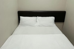 A single bed with a black headboard and white bedding in a room with plain walls. - Hotel Lean Fatt (Ipoh)