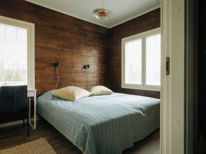 Un dormitorio con una cama, dos almohadas, un escritorio y una silla.