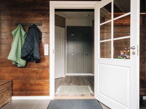 Un interior de madera con una puerta que da a un pasillo, un perchero con chaquetas y un tren de juguete en la puerta.