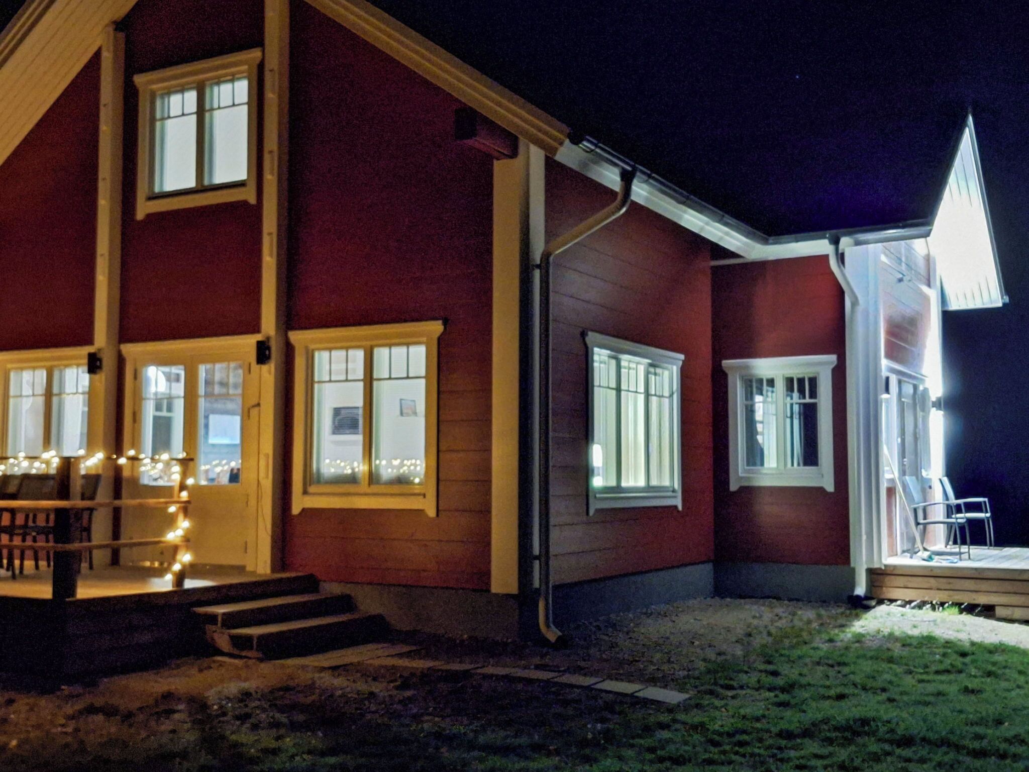 Kaksikerroksinen talo, jossa on kuisti, useita ikkunoita ja hyvin valaistu ulkoasu.