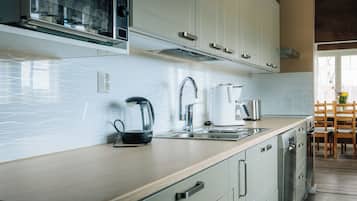 A modern kitchen with a built-in dishwasher, a kettle, and a coffee maker on the countertop.