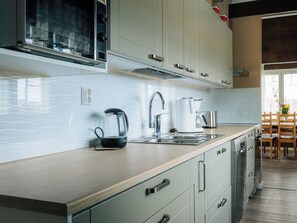 Una cucina moderna con lavastoviglie integrata, bollitore e macchina da caffè sul piano di lavoro.
