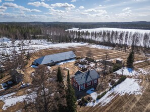 A rural property with a large open field, a barn, and a house with a red facade.