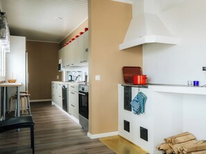 Una cocina moderna con armarios blancos, un horno de acero inoxidable y una olla roja sobre la encimera.