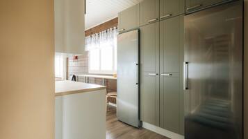 Une cuisine moderne dotée d’un réfrigérateur en acier inoxydable, de meubles en bois et d’une fenêtre offrant une vue agréable.