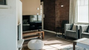 A living room with a TV, sofa, and ottoman.