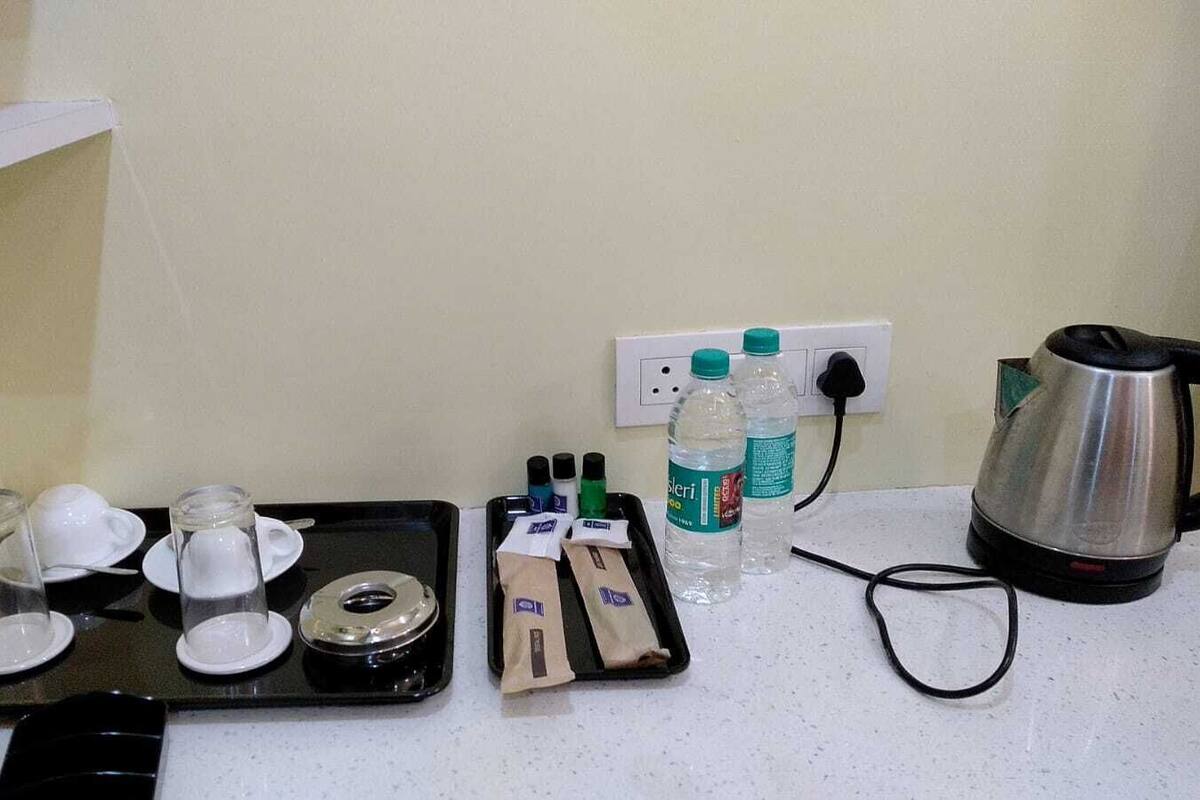 A kitchenette with a coffee maker, tea set, water bottles, and a kettle on a countertop.
