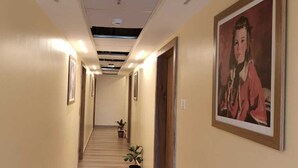 A hotel hallway with framed pictures on the walls, a wooden floor, and a ceiling with recessed lighting. - Forest Transit Hotel (Coimbatore)